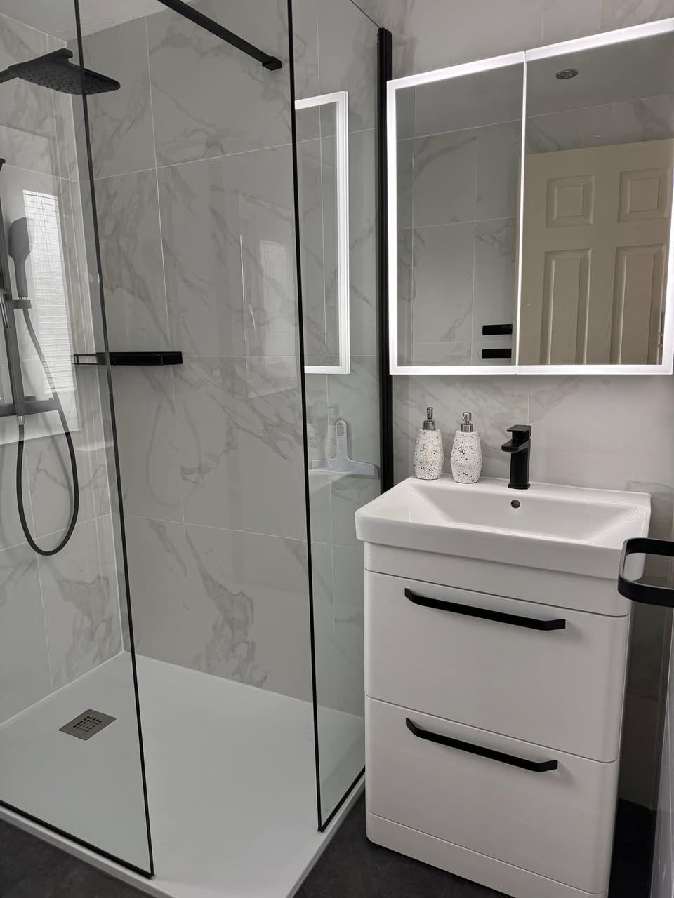 white marble shower room with black taps Otley