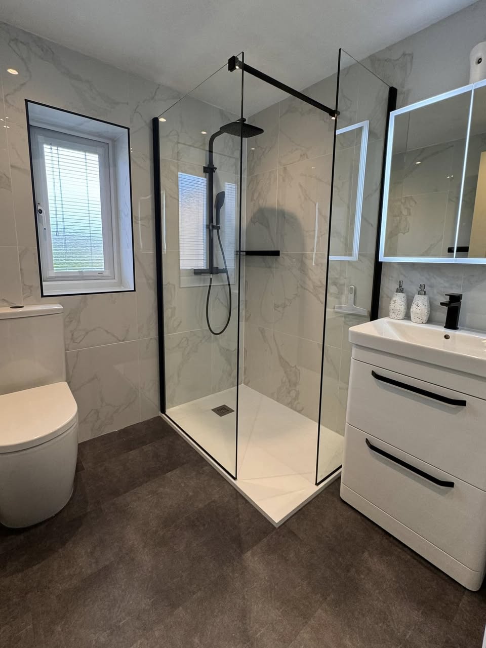 white marble shower room with black taps Otley